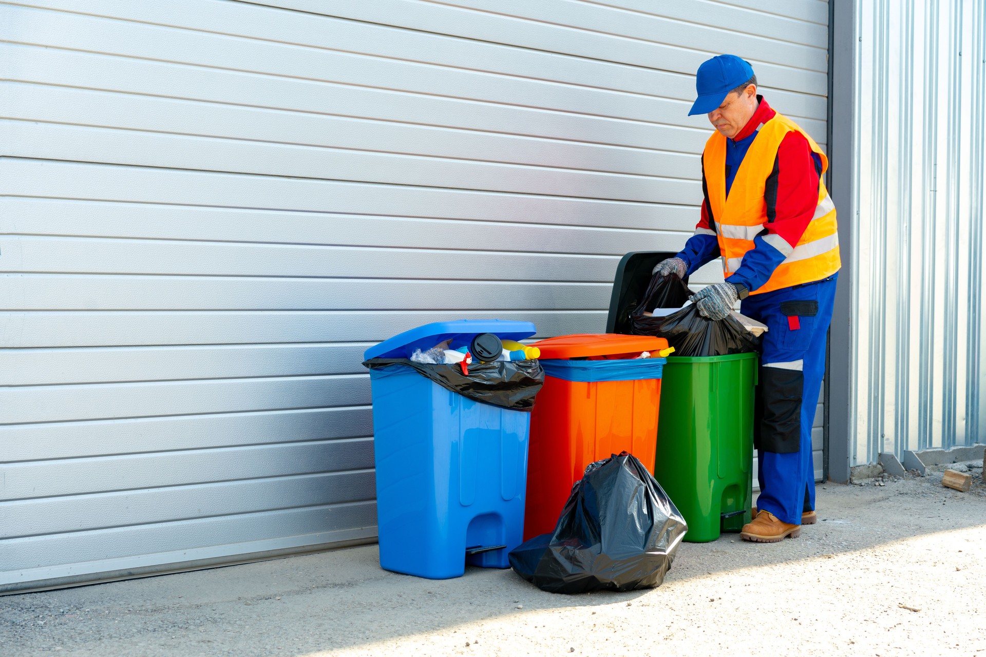 Janitor takes garbage out of trash container outdoors
